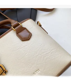 Détail du cuir grainé d'un sac seau bicolore avec des finitions métalliques dorées