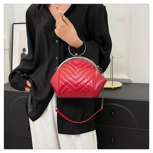 Detail of red quilted shell bag featuring round silver metal handle and vintage clasp