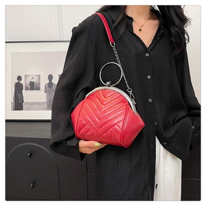 Detail of red V-quilted bag with large circular metal handle and vintage clasp closure