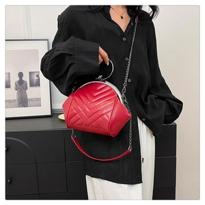 Detail of red quilted shell bag featuring metal clasp and silver circular top handle