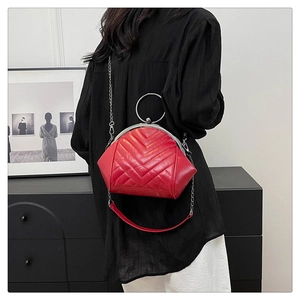 Close-up of red V-quilted crossbody bag with silver ring handle and chain strap on model