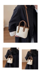 Détail du sac seau crème avec poignées marron et un charmant petit ours doré décoratif