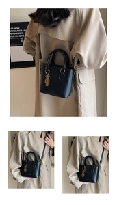 Détail d'un sac seau en cuir verni noir avec pendentif ours doré et double poignée