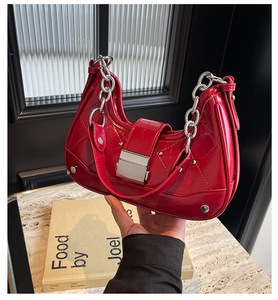 Detail of red quilted patent leather shoulder bag with silver chain and metal buckle