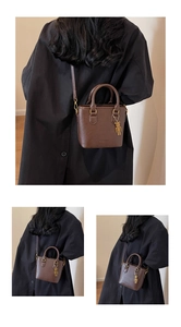 Détail du sac bandoulière vintage marron foncé avec poignée et breloque ours doré