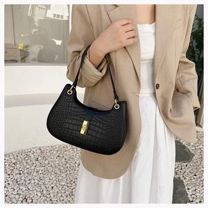 Détail du sac hobo noir à motif crocodile avec boucle dorée et bandoulière élégante