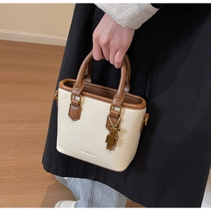 Détails de la texture du cuir et du charm ours sur un sac seau de couleur contrastée