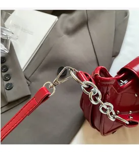 Close-up of red patent leather bag showing silver chain hardware and metallic rivets