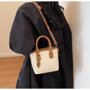 Détail du sac à bandoulière crème et marron en cuir grainé avec pendentif d'ours
