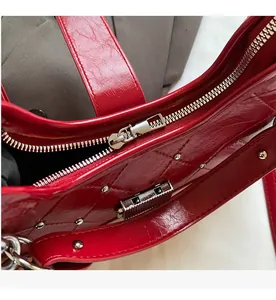 Detailed macro view of smooth silver metal zipper and hardware on red oil wax leather bag