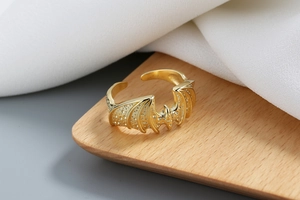 Vue macro d'une bague ouverte aile de chauve-souris dorée sur bois et tissu de soie