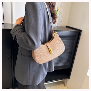 Détail du sac sous le bras marron clair à motif crocodile avec boucle dorée sur blazer gris
