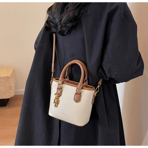 Détail du sac cabas bicolore crème et marron avec pendentif ours doré style KAWS