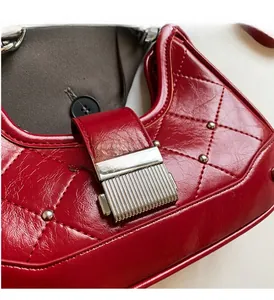 Detailed close-up of quilted red glossy leather shoulder bag with silver push-lock and studs