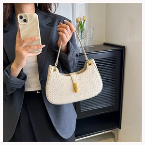 Détail du sac demi-lune crème avec texture crocodile et boucle dorée métallique