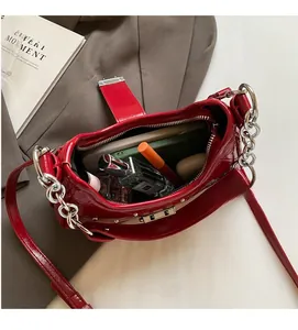 Internal view of red patent leather shoulder bag showing storage for phone and cosmetics