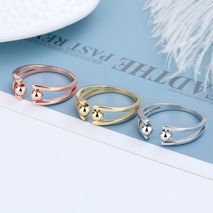 Three minimalist anxiety rings in rose gold, gold, and silver finishes with beads