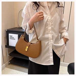 Détail d'un sac hobo marron à motif crocodile avec un fermoir rotatif en métal doré