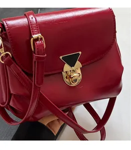 Detail of red faux leather shoulder bag with distinct black and gold triangular metal clasp