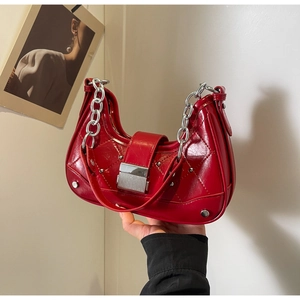 Detail of red quilted leather bag featuring silver studs and chunky chain strap
