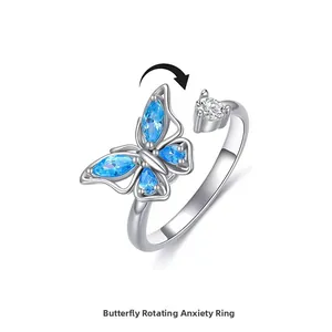 Détail d'une bague rotative papillon argentée avec pierres bleues et fonction rotative