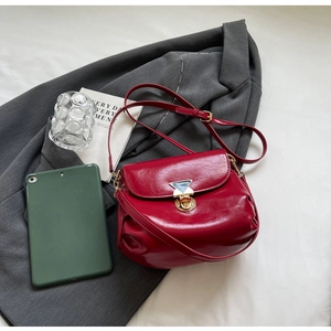 Detail of wine red pleated saddle bag with gold triangle buckle on grey blazer suit