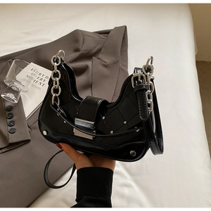 Detail of black patent leather saddle bag with quilted pattern and silver rivet studs
