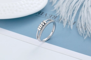 Macro detail of silver rotating ring with zircons and moving beads on blue background