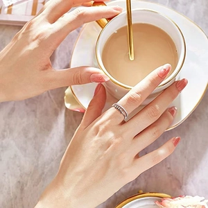 Silver fidget ring with rotating beads worn by model holding a coffee cup at a table