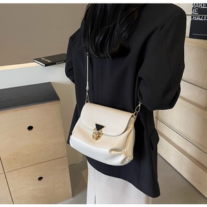Detail of off-white pleated leather shoulder bag with elegant golden triangle metal buckle