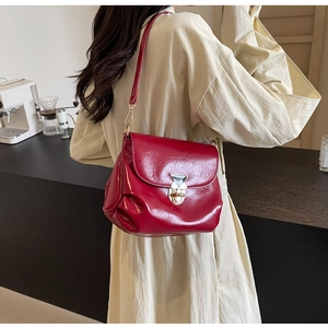Detail of red pleated leather shoulder bag with gold triangular buckle on a model