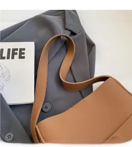Details des breiten Schultergurts und der Litchi-Lederstruktur der braunen Tasche