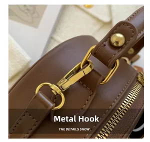 Detail of vintage gold hardware hook and textured brown lychee grain leather bag