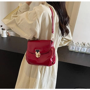 Detail of red patent leather shoulder bag featuring a gold buckle and flap closure