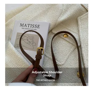 Close-up of adjustable brown leather shoulder strap with gold buckle on leopard print bag