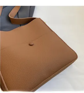 Detail der braunen Bucket Bag aus Leder mit weicher Litschi-Maserung und Nähten