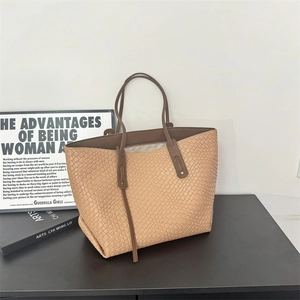 Large woven tote bag in light coffee faux leather with brown straps on a sleek table