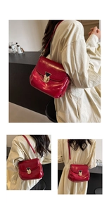 Detail of red glossy leather shoulder bag featuring a gold metal twist lock and fine strap