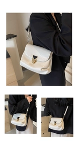 Detail of white patent leather shoulder bag with gold triangular clasp and pleated finish