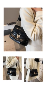 Detail of black glossy leather bag featuring a gold triangular buckle and adjustable strap
