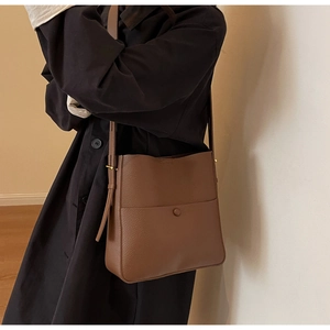Detail der karamellbraunen Beuteltasche mit Lychee-Struktur am Modell getragen