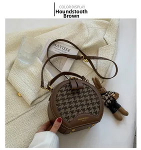 Close-up of a coffee houndstooth round crossbody bag with a cute bunny charm