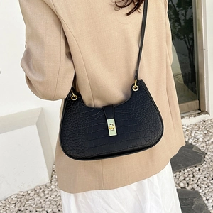 Sac à bandoulière rétro noir à motif crocodile avec fermoir doré porté par un mannequin