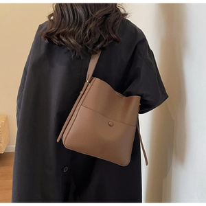 Detail der braunen Beuteltasche aus genarbtem Leder mit Schnallentasche und Textur