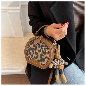 Detail of round leopard print crossbody bag with gold logo and plush rabbit charm
