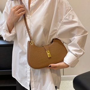 Sac bandoulière marron motif crocodile avec boucle dorée porté sur une chemise blanche