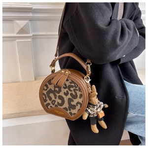 Detail of round leopard print crossbody bag with plush rabbit charm and gold logo