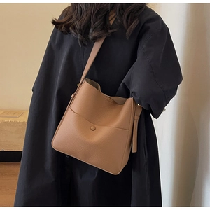 Detail der braunen Bucket Bag mit Litschi-Muster und Vordertasche am Model gezeigt