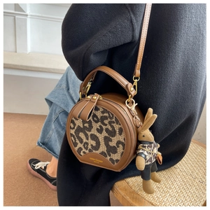 Detail of round leopard print crossbody bag with a cute rabbit plush charm