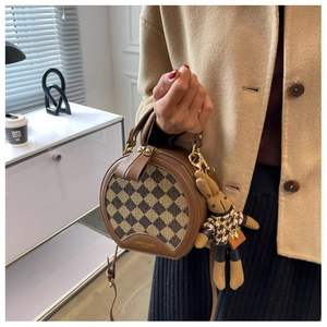 Close-up of a round checkered crossbody bag with a cute knitted bunny charm detail